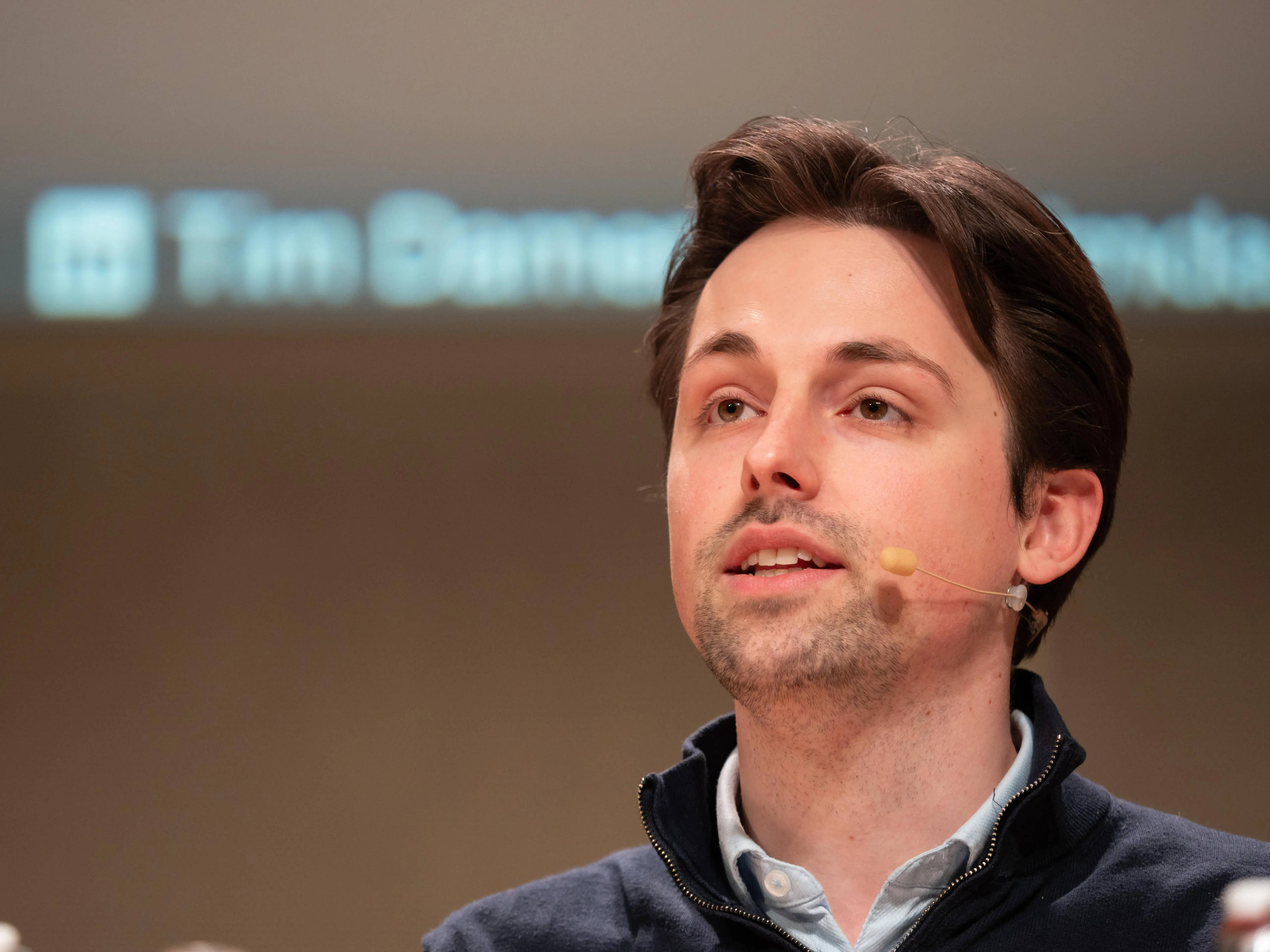 Tim Damen speaking on stage with microphone attached to his ear